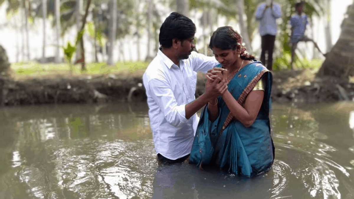 Indian man baptizing lady