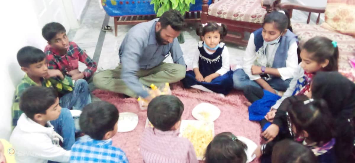 Pakistan Biblical Unitarian Pastor eating on floor with children