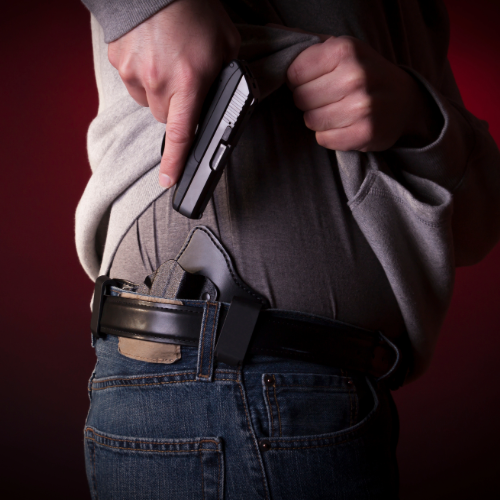man pulling a concealed gun from his belt