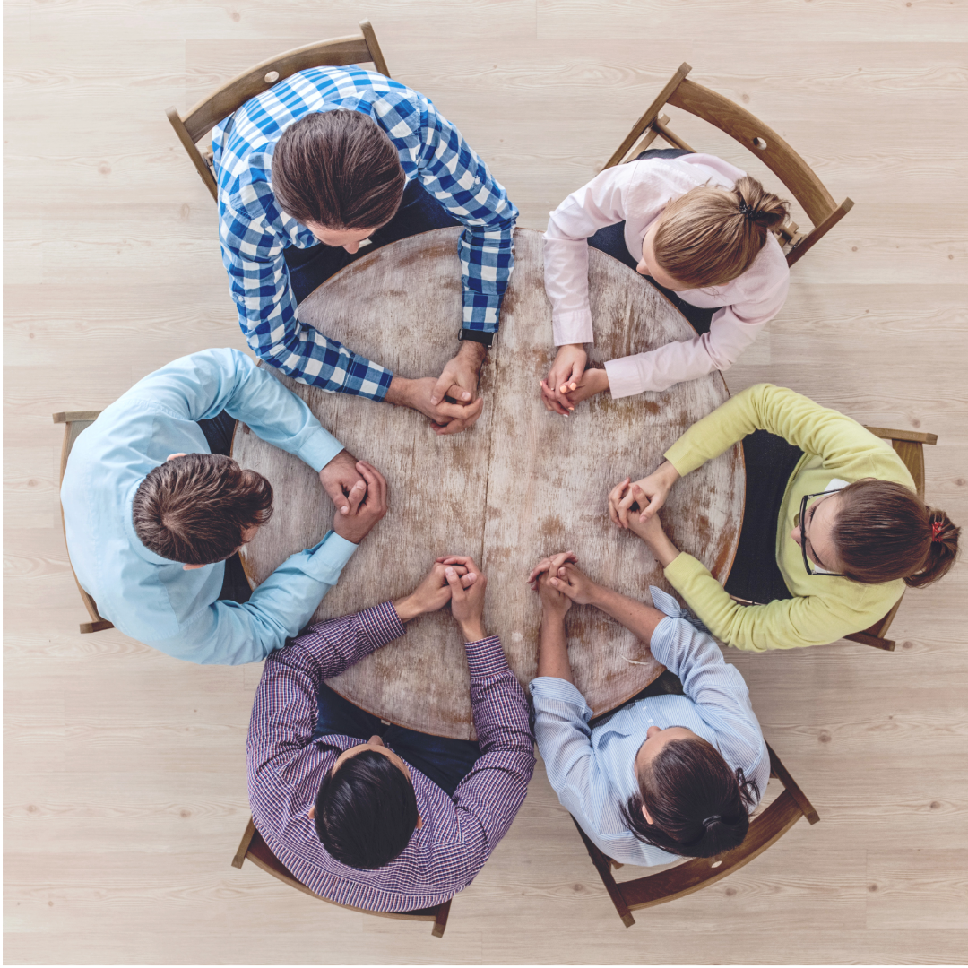 6 people sitting around a round table having a discussion